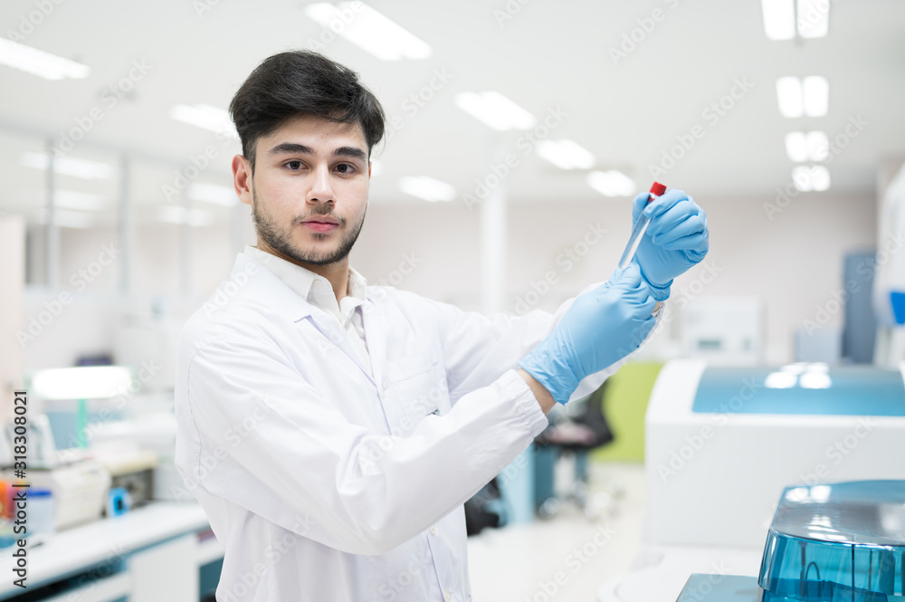 Portrait scientist man holding test tube and standing with automatic machine in laboratory.Researcher analysis blood chemistry in medical laboratory. Medical healthcare technology research concept.