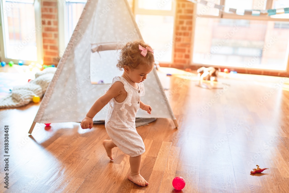 Beautiful caucasian infant playing with toys at colorful playroom. Happy and playful at kindergarten. Beautiful caucasian infant playing with toys at colorful playroom. Happy and playful at kindergarten.
