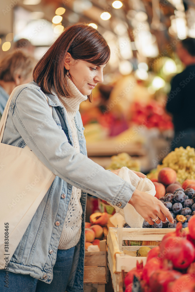 Woman is chooses fruits and vegetables at food market. Reusable eco bag for shopping. Sustainable lifestyle. Eco friendly concept. Woman is chooses fruits and vegetables at food market. Reusable eco bag for shopping. Sustainable lifestyle. Eco friendly concept.