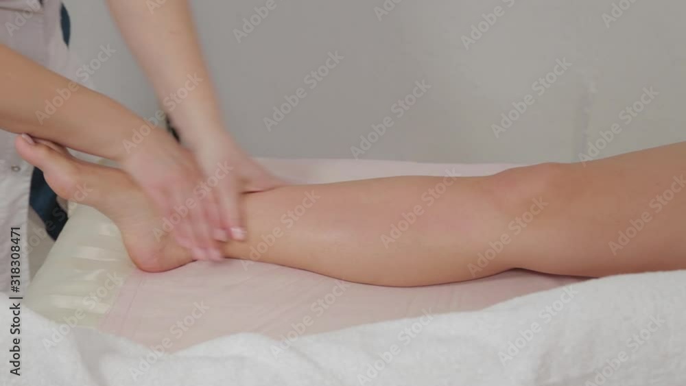 Female massage therapist doing massage over the entire length of the legs of a young girl. Female massage therapist doing massage over the entire length of the legs of a young girl.