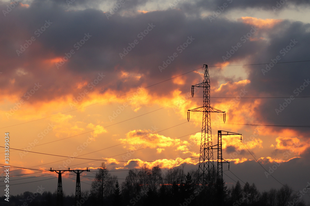 High voltage electric lines cross the hilly mestnost. Electric station in the summer under the open sky. Power industry. Ecology of nature. Metal technological structures. Strategic object in sunset