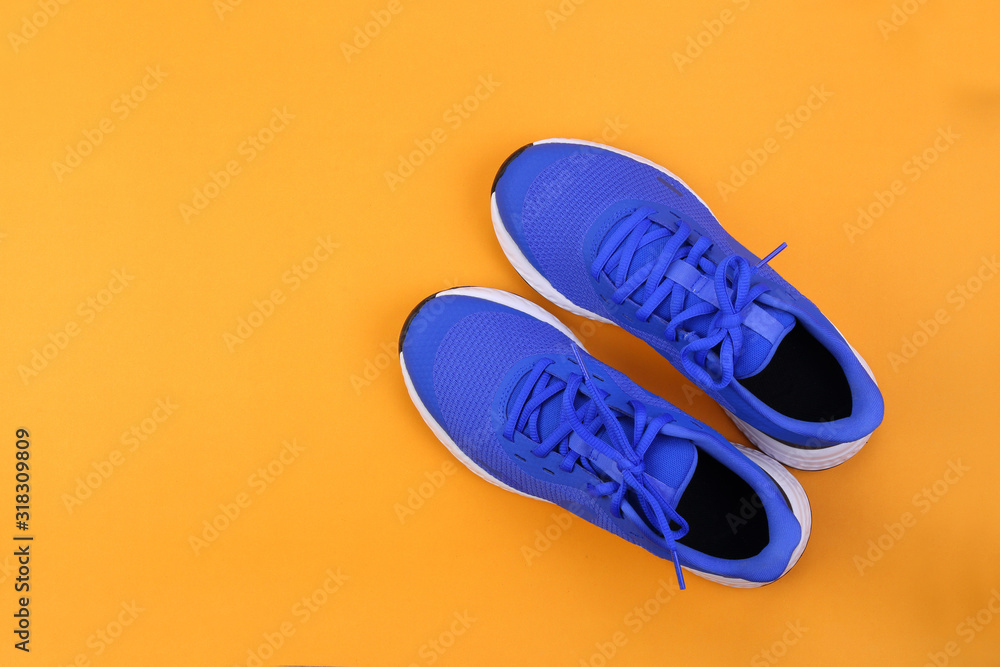 Top view blue running shoes on orange pastel background - obrazy, fototapety, plakaty 