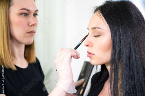 Makeup artist doing the make up for beautiful brunette woman