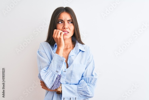 Young beautiful woman wearing blue elegant shirt standing over isolated white background looking stressed and nervous with hands on mouth biting nails. Anxiety problem. © Krakenimages.com