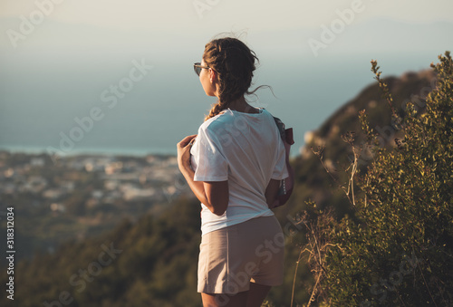 A beautiful slender young girl looks at the beautiful panorama.