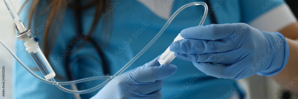 Fotografie, Obraz Female nurse hand in blue protective gloves hold dropper against medicine hospital background