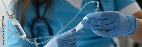 Female nurse hand in blue protective gloves hold dropper against medicine hospital background. Medical education concept photo