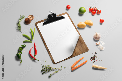 Organic food background. Food photography different vegetables and cliboard menu template on grey background. Copy space, isometric view photo