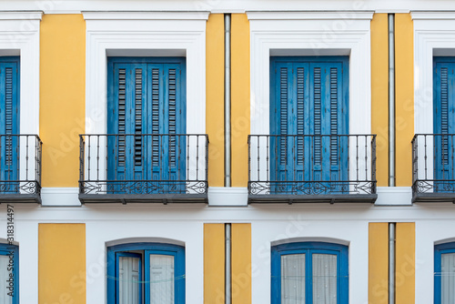 Colorful spanish facade with balconies and blue shutters