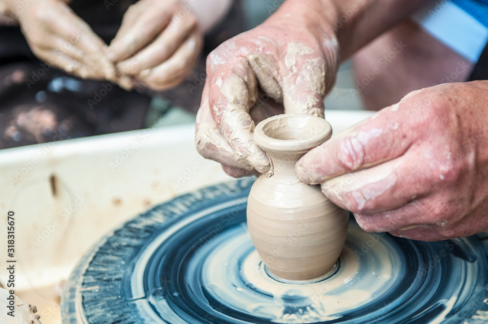 The potter makes pottery dishes on potter's wheel. The potter makes pottery dishes on potter's wheel.