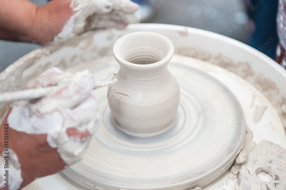 The potter makes pottery dishes on potter's wheel.