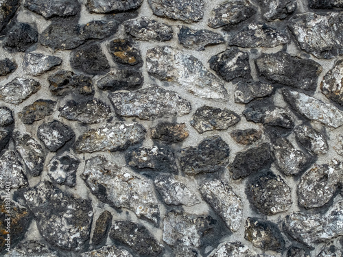 wall of large visible multicoloured stones with cement all around