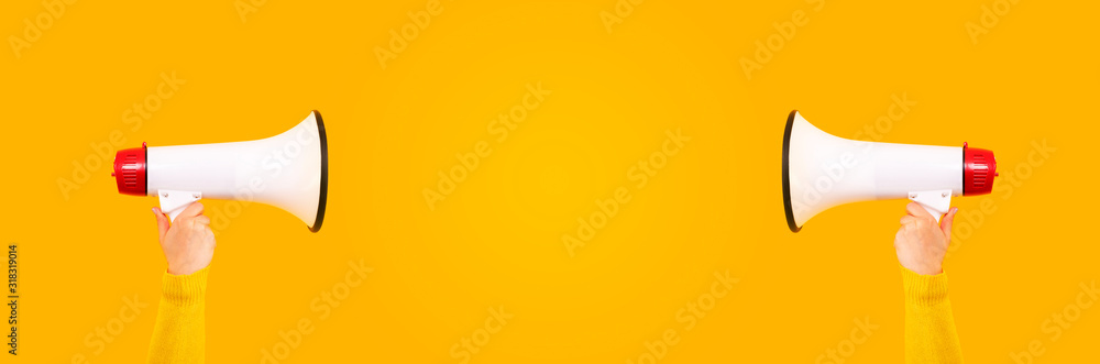 Fototapeta premium megaphones in hands on a yellow background, panoramic mock-up image with space for text, attention concept announcement