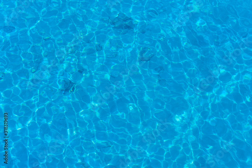 Background of water in blue swimming pool  water surface with a sun reflection