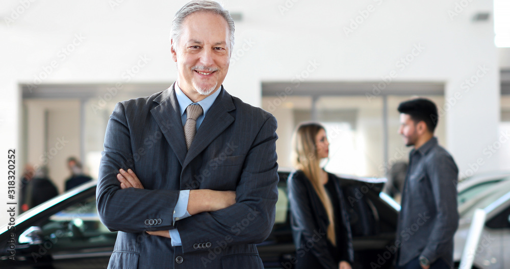 Happy male car dealer principal inside showroom Happy male car dealer principal inside showroom