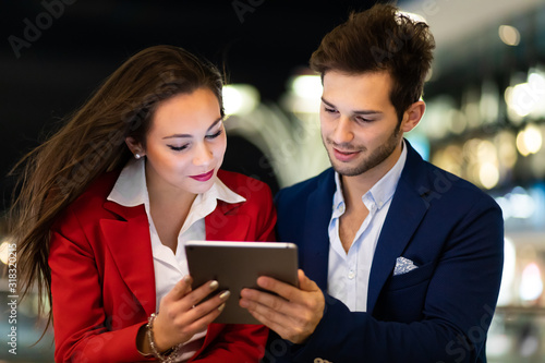 Couple of business people using a tablet outdoor at night in a modern city setting