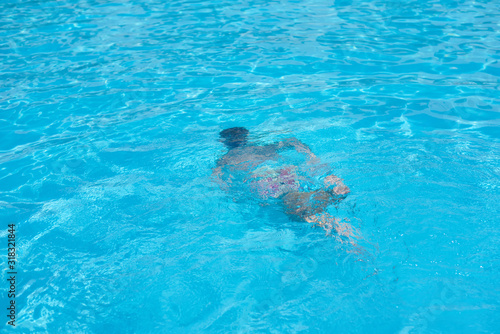 Boy in diving mask swim underwater in the swimming pool