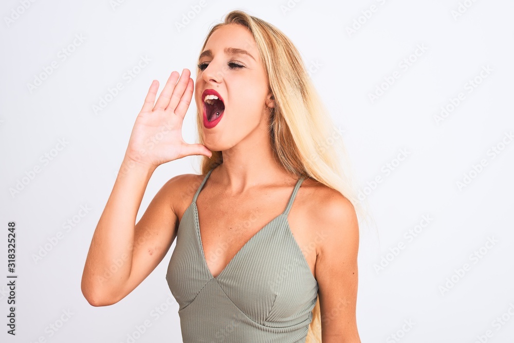Young beautiful woman wearing casual green t-shirt standing over isolated white background shouting and screaming loud to side with hand on mouth. Communication concept. Young beautiful woman wearing casual green t-shirt standing over isolated white background shouting and screaming loud to side with hand on mouth. Communication concept.