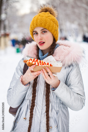 Portrait of a young beautiful woman in a ski suit posing in winter park photo