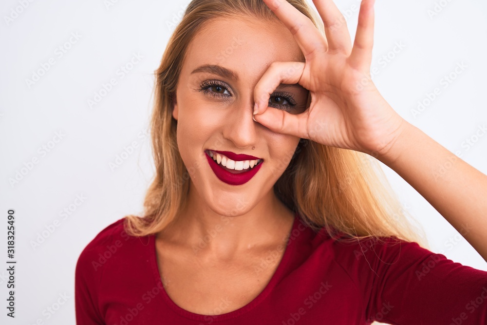 Young beautiful woman wearing red t-shirt standing over isolated white background with happy face smiling doing ok sign with hand on eye looking through fingers Young beautiful woman wearing red t-shirt standing over isolated white background with happy face smiling doing ok sign with hand on eye looking through fingers