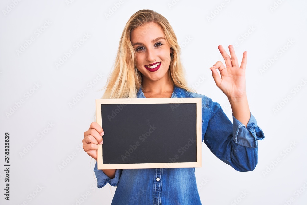 Young beautiful teacher woman holding blackboard standing over isolated white background doing ok sign with fingers, excellent symbol Young beautiful teacher woman holding blackboard standing over isolated white background doing ok sign with fingers, excellent symbol