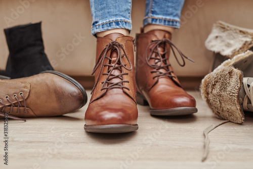 Woman chooses comfortable brown leather shoes among bunch of the different pairs