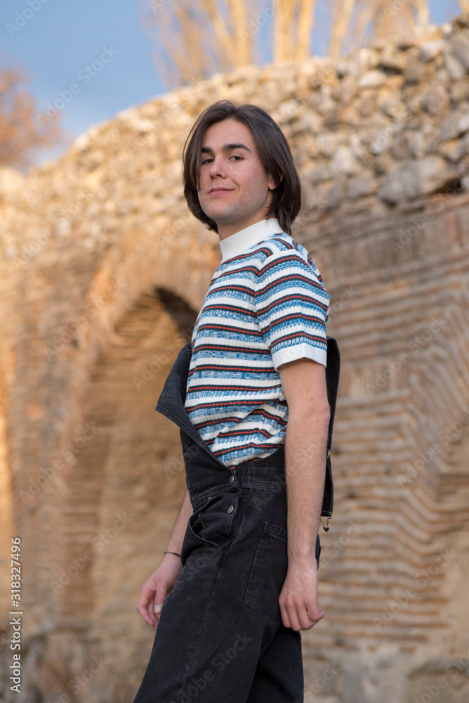 Young man posing in the field and with a bridge in the background. Enjoying the outdoors Young man posing in the field and with a bridge in the background. Enjoying the outdoors