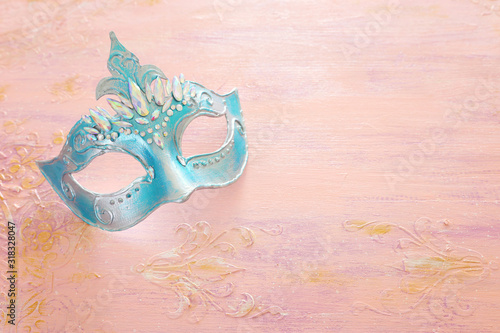 Photo of elegant and delicate blue Venetian mask over pastel wooden background