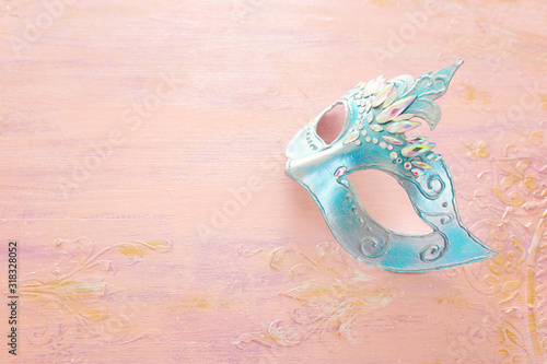 Photo of elegant and delicate blue Venetian mask over pastel wooden background