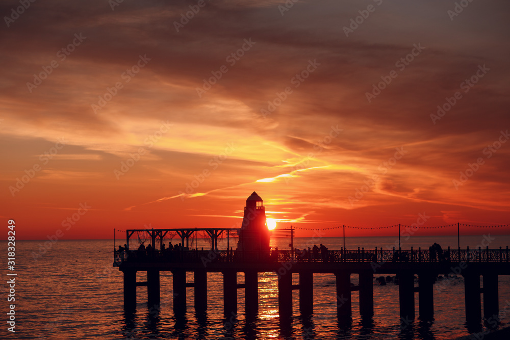 Lighthouse pier and setting sun over the water