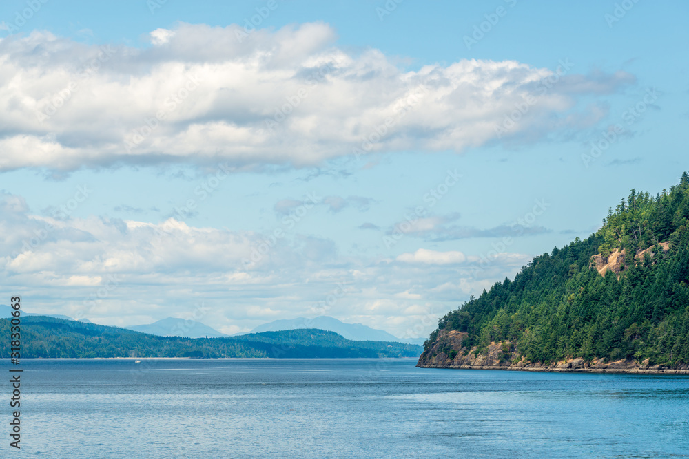 View over inlet, ocean and island with boat and mountains in beautiful British Columbia. Canada.