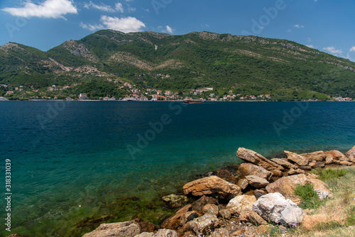 Bay of Kotor, also known as Kotorska Boka, during a quiet summer afternoon with mountains reflecting in the waters of the Adriatic sea.