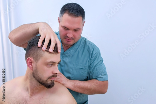 Man on preventive examination of doctor chiropractor on neck diagnostic. Manual therapist turning patient's head in different sides to make a diagnosis and find problem. Manual physician.