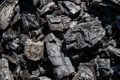 Ash of a burned-out fire. Background of burnt firewood. Background with black burnt wood. Charcoal texture backdrop. Bonfire covered with ashes and sawdust closeup