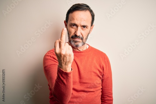 Middle age hoary man wearing casual orange sweater standing over isolated white background Showing middle finger, impolite and rude fuck off expression