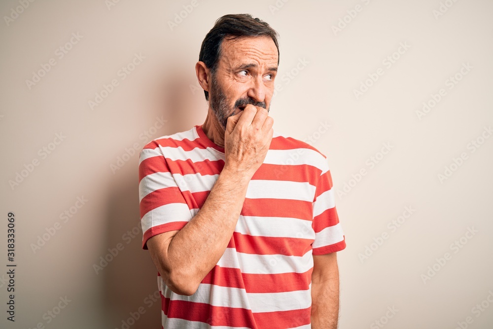 Middle age hoary man wearing casual striped t-shirt standing over isolated white background looking stressed and nervous with hands on mouth biting nails. Anxiety problem. Middle age hoary man wearing casual striped t-shirt standing over isolated white background looking stressed and nervous with hands on mouth biting nails. Anxiety problem.