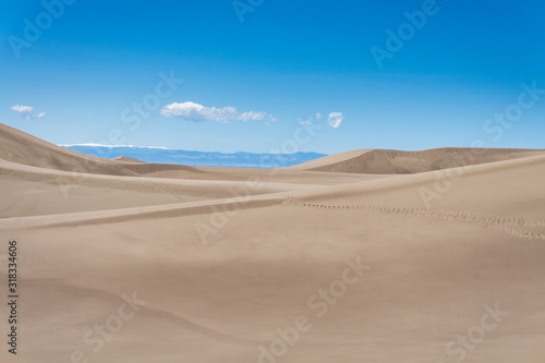 Giant sand dune landscape with clear blue sky with snow and mountain in the background