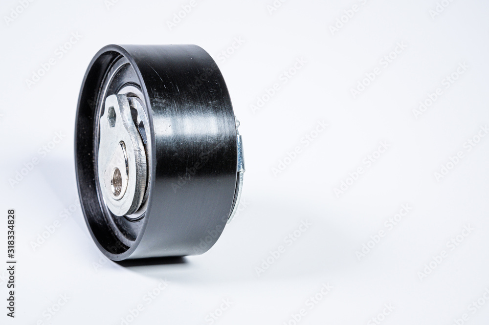 Tension roller of a timing belt of an internal combustion engine on a gray background. The concept of new spare parts and maintenance of vehicles Tension roller of a timing belt of an internal combustion engine on a gray background. The concept of new spare parts and maintenance of vehicles