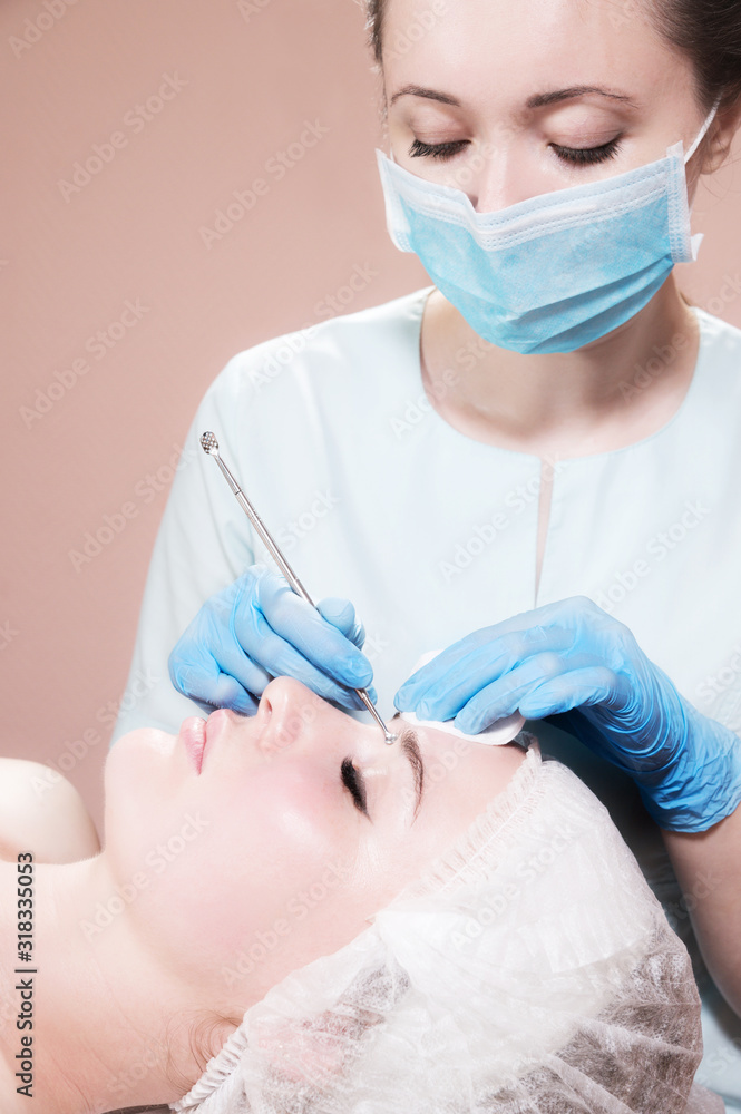 A professional procedure for cleaning the skin with a steel tool for acne and acne in a beauty parlor. Deep cleansing of a woman's face with a blackhead remover in a beauty salon. A professional procedure for cleaning the skin with a steel tool for acne and acne in a beauty parlor. Deep cleansing of a woman's face with a blackhead remover in a beauty salon.