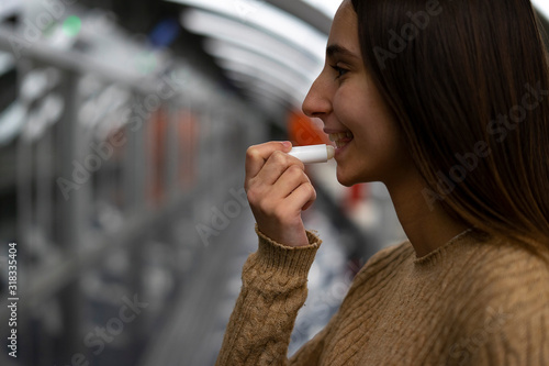 Young woman putting lipstick and cocoa cream on her lips.
