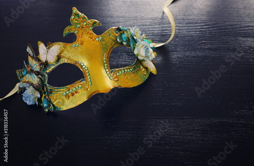 Photo of elegant and delicate gold Venetian mask over dark wooden background