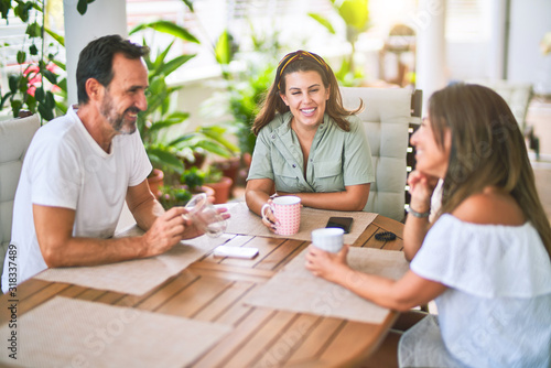 Beautiful family sitting on terrace drinking cup of coffee speaking and smiling