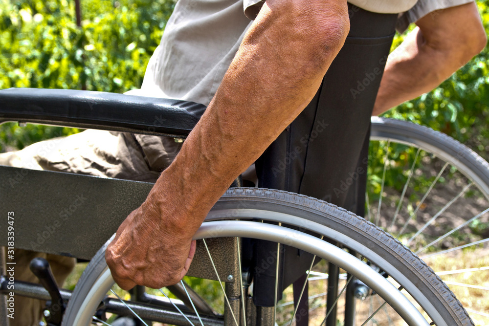 A disabled man is sitting in a wheelchair ,Holds his hands on the wheel. Handicap people Concept. A disabled man is sitting in a wheelchair ,Holds his hands on the wheel. Handicap people Concept.