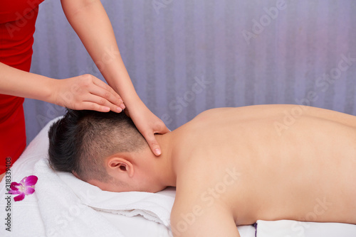 Horizontal side view shot of unrecognizable man getting relaxing massage for head and neck in modern spa salon