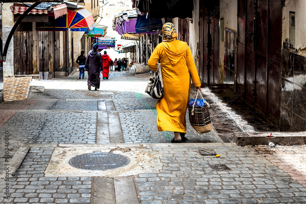 Fes, Morocco - 21,04, 2019: People walking in the street of the open-air market bazaar in Fez. Fes, Morocco - 21,04, 2019: People walking in the street of the open-air market bazaar in Fez.