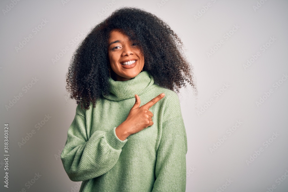 Young beautiful african american woman with afro hair wearing green winter sweater cheerful with a smile of face pointing with hand and finger up to the side with happy and natural expression on face Young beautiful african american woman with afro hair wearing green winter sweater cheerful with a smile of face pointing with hand and finger up to the side with happy and natural expression on face