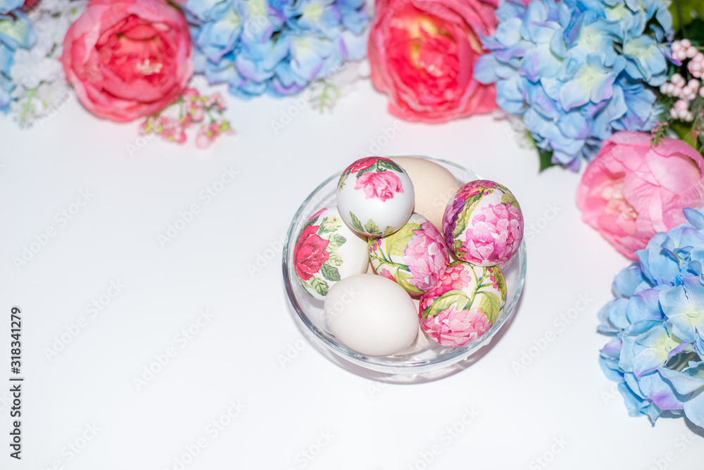bowl with Easter eggs in a floral pattern on a white background with flowers. Space for text.