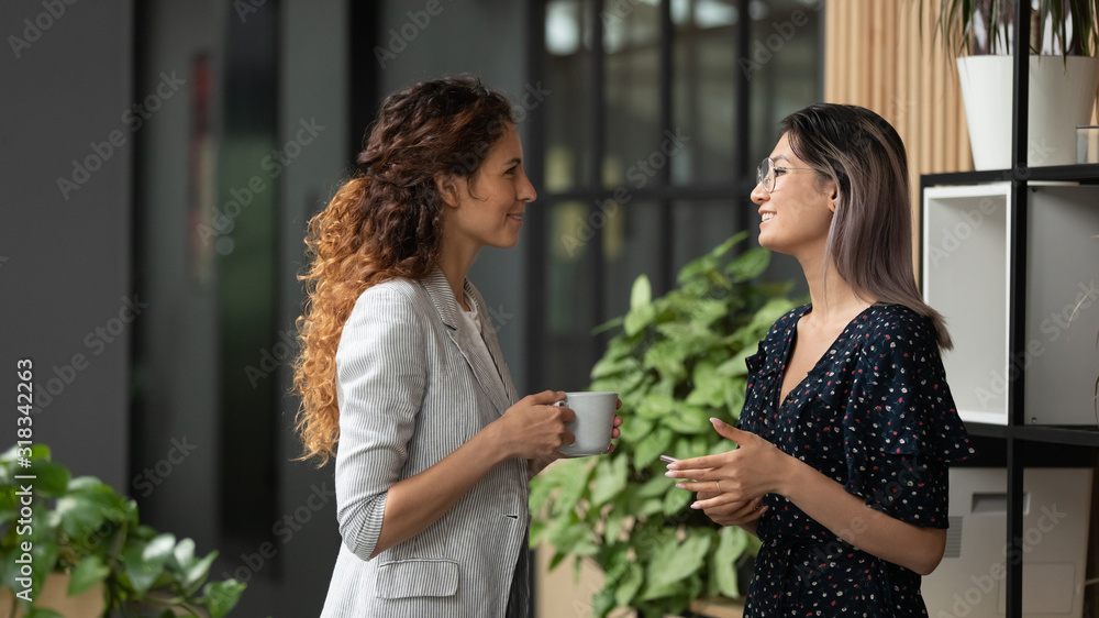 Multiethnic female colleagues chat during coffee break