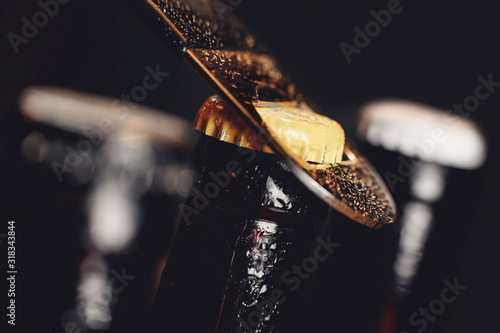 Glass ice cold bottles of beer with opener cap on dark background