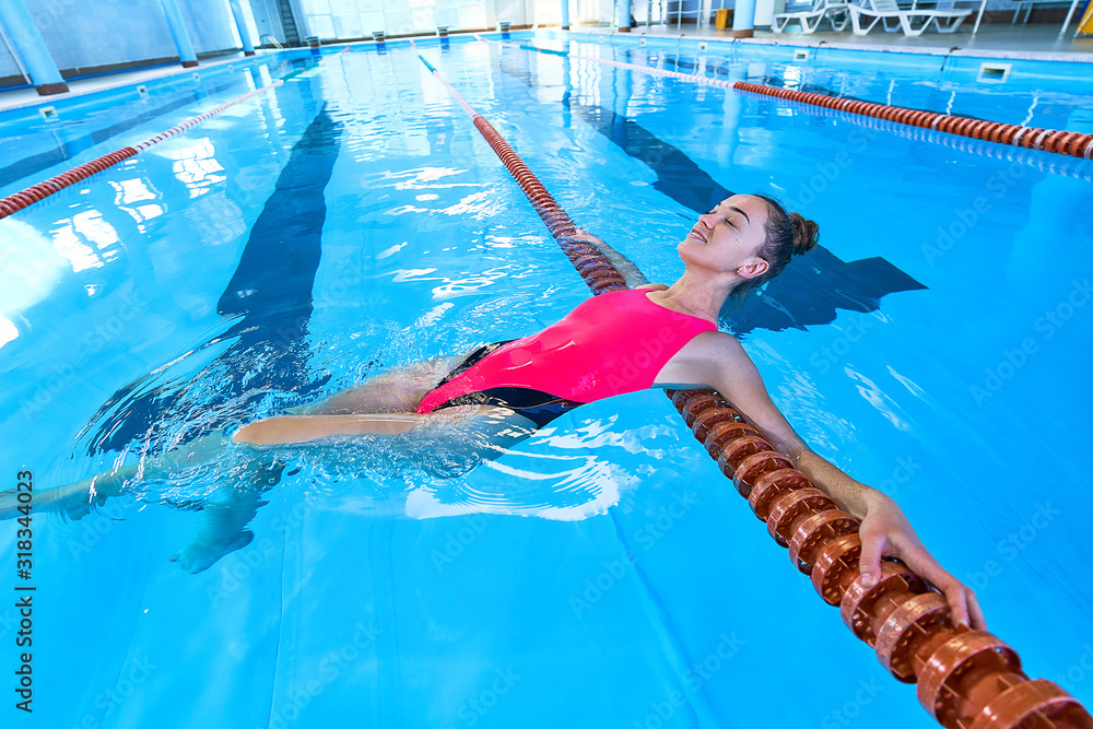 Young fitness swimmer woman in swimsuit during relaxing in swimming pool in leisure centre
